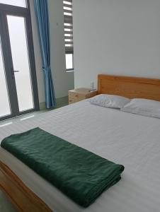 a bedroom with a bed with a green blanket on it at Khách sạn Đạt Tiến Quân in Ấp Bình Hưng