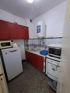 a small kitchen with white appliances and red cabinets at Tucumán y Colón in Mar del Plata