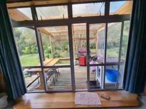an open door to a patio with a table and chairs at Sub-Tropical Paradise Retreat Willow Creek Cabin with Access to Sauna in Totara North