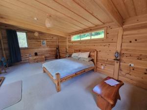 Totara NorthSub-Tropical Paradise Retreat Willow Creek Cabin with Access to Sauna的小木屋内的卧室,配有床 更多7张照片