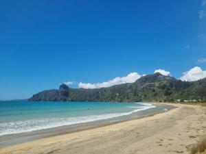 Totara NorthSub-Tropical Paradise Retreat Willow Creek Cabin with Access to Sauna的享有海滩美景,背景为群山