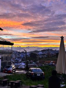 a sunset with cars parked in a parking lot at Nhà Của Nắng - Homestay Đà Lạt in Da Thanh