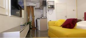 a living room with a yellow couch and a kitchen at Micangelo shortlet apartment in Idimu +42 photos