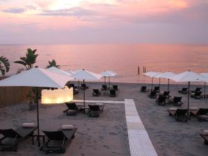 eine Gruppe von Stühlen und Sonnenschirmen am Strand in der Unterkunft Hotel Caparena in Taormina