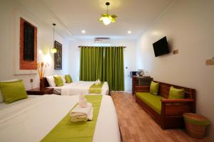 a hotel room with two beds and a green curtain at Angkor Rithy Residences in Siem Reap