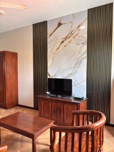 ein Wohnzimmer mit einem Holztisch und einem TV in der Unterkunft AiRia Hotel Port Dickson in Sirusa + 9 Fotos