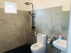 a bathroom with a white toilet and a sink at Calidan in Mirissa