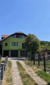ein grünes Gebäude mit Zaun neben einem Feldweg in der Unterkunft Panonska jezera ZELENA OAZA in Tuzla