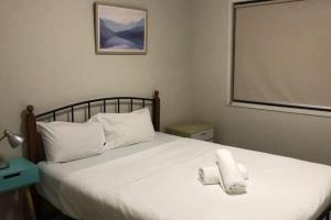 Geelong 3 Bedroom Lovely House في Hamlyn Heights: غرفة نوم بها سرير عليه منشفتان