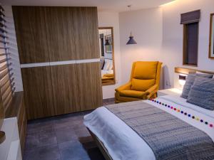 een slaapkamer met een bed en een gele stoel bij The Lu'um House in Tuxtla Gutiérrez