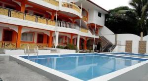 a hotel with a swimming pool in front of a building at Palm Grove Saud Holiday Complex Hotel in Burayoc