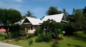 a house with a white roof on a green lawn at Monn Phu Phrai in Ban Pong