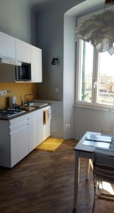 cocina con armarios blancos, mesa y ventana en L'affresco, en La Spezia