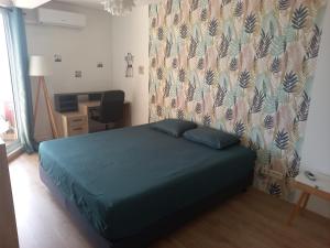 a bedroom with a blue bed and a desk with a chair at Appartement 2 chambres centre Papeete vue Moorea in Papeete