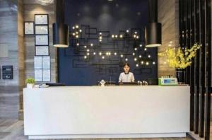 福州Echarm Hotel Fuzhou Sanfang Qixiang East Street Metro Station的坐在一个房间接待台的女人