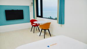 Una habitación con dos sillas y una mesa y un televisor. en 안목을높이다 펜션, en Kyŏnso