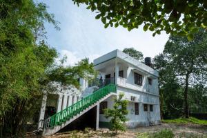 an old white building with a green staircase on it at Marari Oommen's Villa in Vayalār