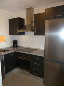 a kitchen with brown cabinets and a stainless steel refrigerator at Apartamento Isla de Terrazas de la Torre in Roldán