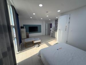 Un dormitorio con una cama blanca y un televisor. en 안목을높이다 펜션, en Kyŏnso