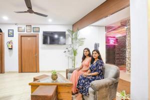 two women sitting on a couch in a living room at FabHotel Duke Inn in Bhopal