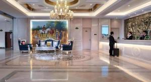 ein Mann steht in einer Lobby mit einem Gemälde an der Wand in der Unterkunft Vienna Hotel Jiangsu Zhangjiagang Passenger Terminal Station in Zhangjiagang