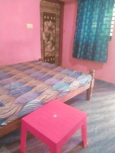 a pink bedroom with a bed and a red stool at Gokarna 2Bhk,Kitchen,AC and Non AC Stay in Gokarna