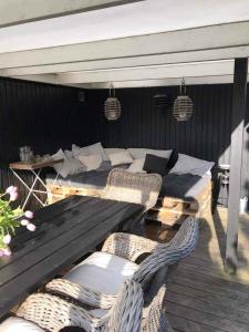 a patio with two beds and wicker chairs on a deck at Lovely Holiday Home With Annex And Garden in Dronningmølle +14 photos