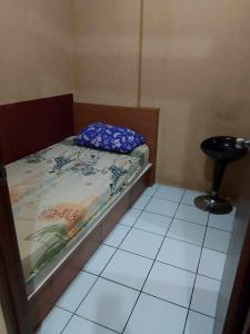 a small bedroom with a bed and a stool at Aparta Homestay in Pekayon Satu