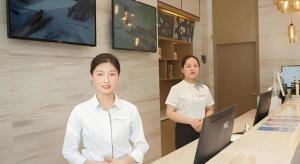 苏州City Comfort Inn Suzhou Wujiang Development Zone Yundong的站在手提电脑柜台前的妇女