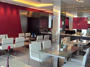 ein Restaurant mit weißen Stühlen und Tischen und einer roten Wand in der Unterkunft Jinjiang Inn Zhuhai Xiangzhou Qinglv Middle Road Theater in Zhuhai