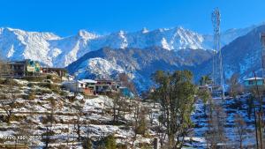 マクロード・ガンジにあるAbhi houseの雪に覆われた山々のある雪の丘の上の住宅群