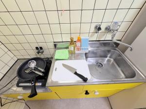 eine Küchentheke mit einer Spüle und einem Messer in der Unterkunft ハイツ緑ヶ丘103 in Nagasaki