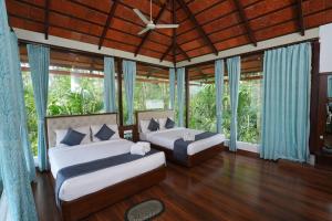 VastāraRG The Grand Haven Resort的一间带两张床和吊扇的卧室