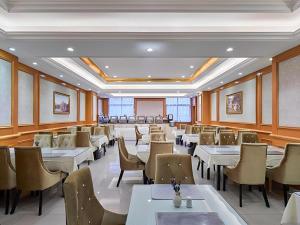 西安Vienna Hotel Xi'an Zhonglou的摆放着白色桌椅的餐厅