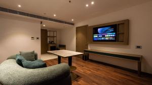 sala de estar con 2 sillas y TV en la pared en Coral Reef Kakkanad, en Kochi