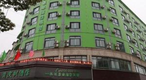 a green building with an american flag on it at Vatica Hangzhou Linan Qianwang Street Hotel in Lin'an