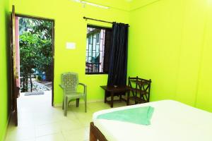 una camera da letto con pareti verdi, un letto e una sedia di The Valley Arambol ad Arambol