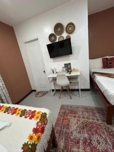 a living room with a bed and a desk with a television at Morocco Hotel El Nido in El Nido