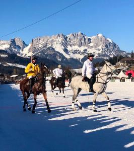 a group of people riding horses in the snow at JUCHEEE ChaletSuite in Tonis cozy Guesthouse by Alpin Charme Apartments in Reith bei Kitzbühel