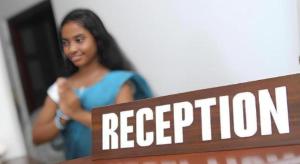 KadirandolaThe MGS Hotel的站在一个旁读招待会的标志上的女人