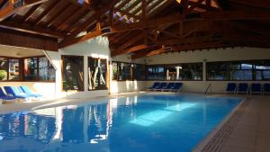 uma grande piscina com cadeiras azuis e um tecto de madeira em Costa Brava Apart Hotel & Suites em San Carlos de Bariloche