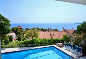 a swimming pool with chairs and the ocean in the background at Art Blue Residence - Panorama Maisonette in Aghia Marina