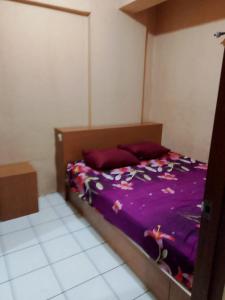 a bed with a purple comforter in a room at Aparta Homestay in Pekayon Satu