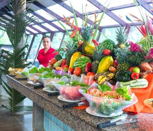 a woman standing behind a buffet of fruits and vegetables at Pachira Lodge in Tortuguero