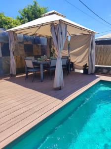 a deck with a table and a tent next to a pool at L'évidence St André in Le Patelin