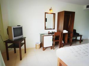 盼武里Bacchus Home Resort的一间带床、电视和书桌的卧室