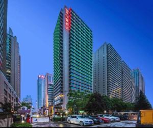ein hohes Gebäude mit Autos auf einem Parkplatz in der Unterkunft Xian Yohol Hotel in Xi'an
