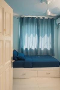 a bed in a room with a blue curtain at Dhonveli in Male City