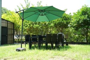 a table and chairs under an umbrella in the grass at Private stay MIYAJIMA tonbo-AND in Hatsukaichi
