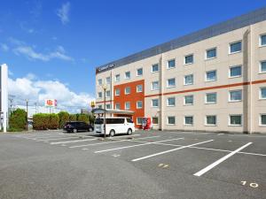 a white van parked in a parking lot in front of a building at Comfort Inn Tsuchiura Ami in Tsuchiura